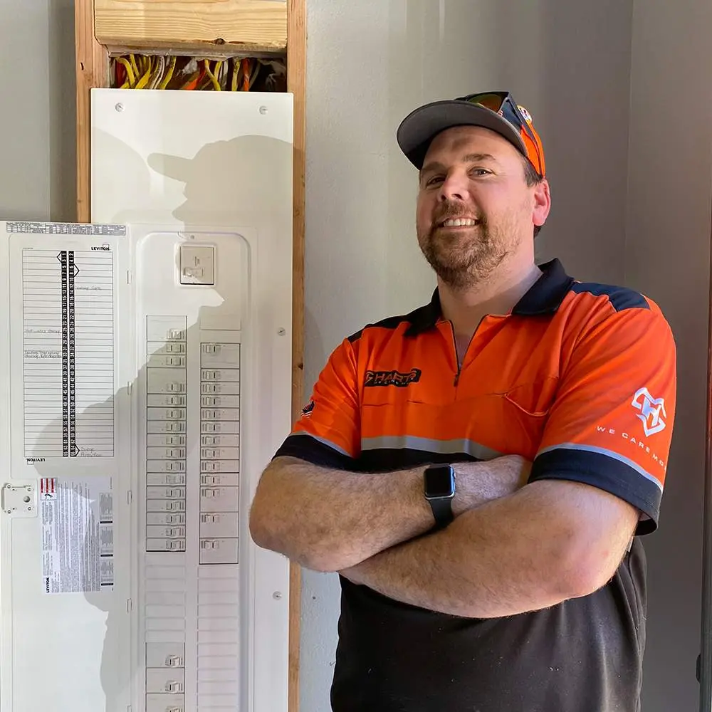 Licensed Harts electrician standing next to an open electrical panel in Tacoma, WA.
