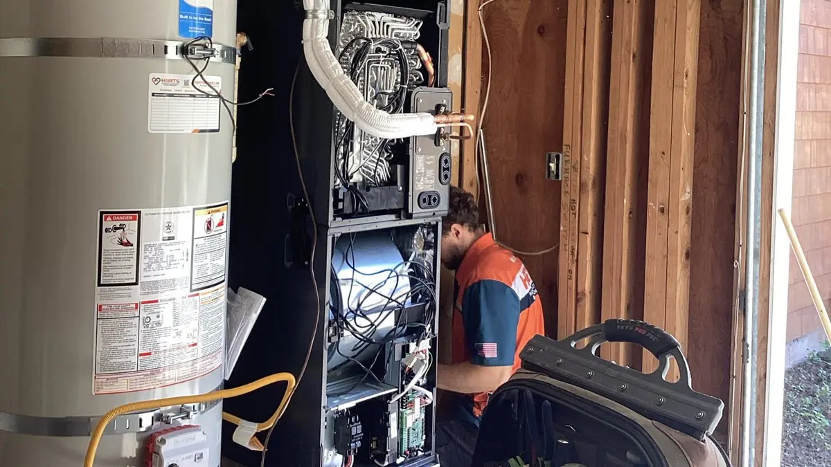 Harts HVAC technician servicing a high-efficiency furnace in a home garage