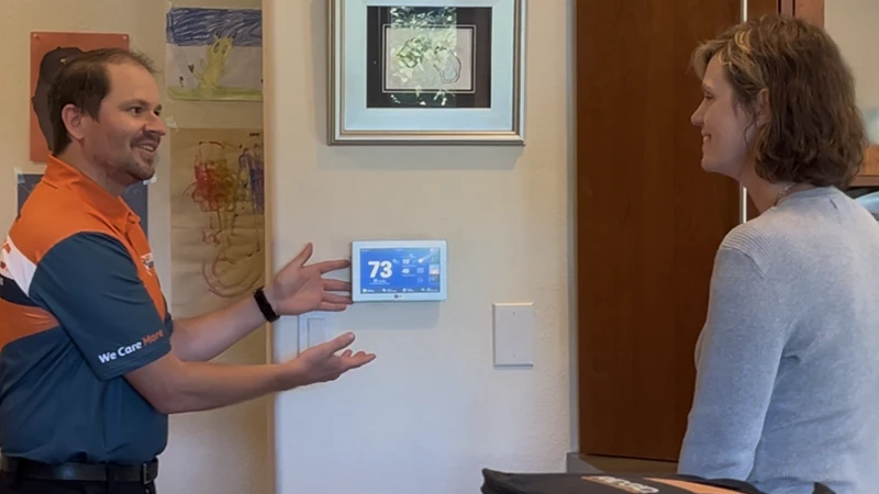 Harts HVAC technician explaining a smart thermostat installation to a Renton homeowner