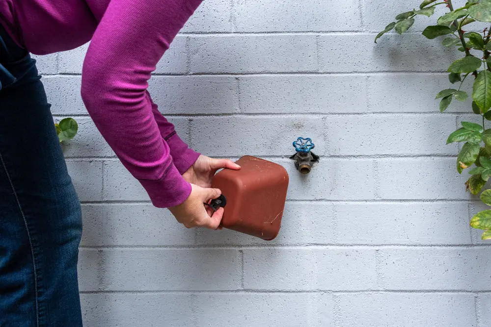 Person installing an insulated cover over an outdoor hose bib