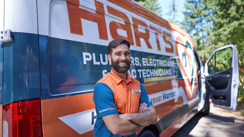 Harts Silverdale plumbing technician standing beside service van with arms crossed