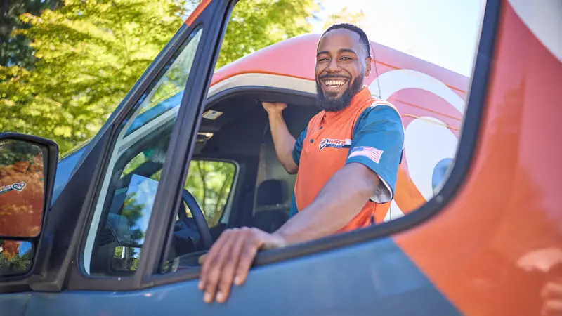 Friendly Harts technician smiling beside a Harts service van in Seattle, WA.