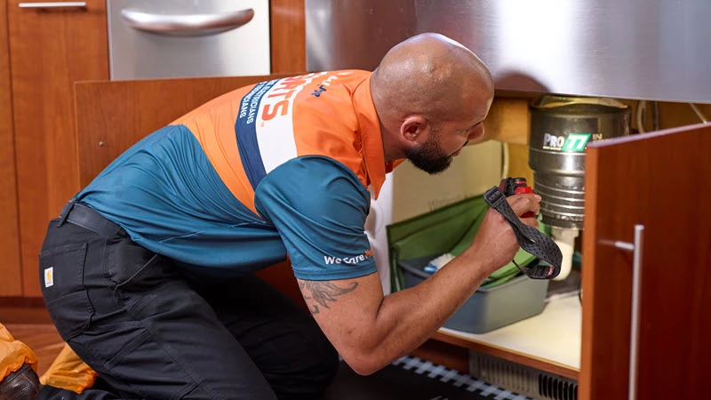 Harts plumber performing a sink plumbing repair inside a Seattle home.