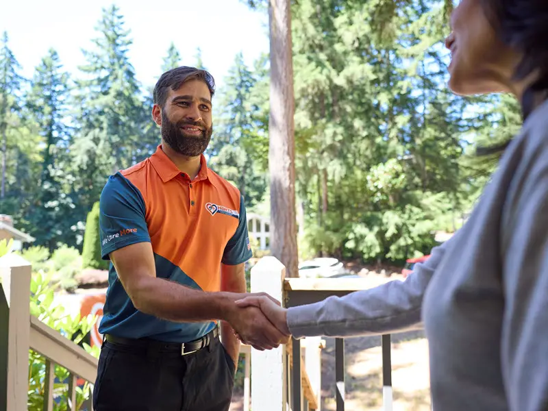 A smiling and respectful technician shaking hands with a customer, a known green flag for a good contractor.