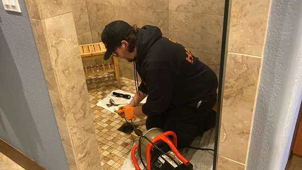 Plumber performing a drain cleaning using a professional drain snake.