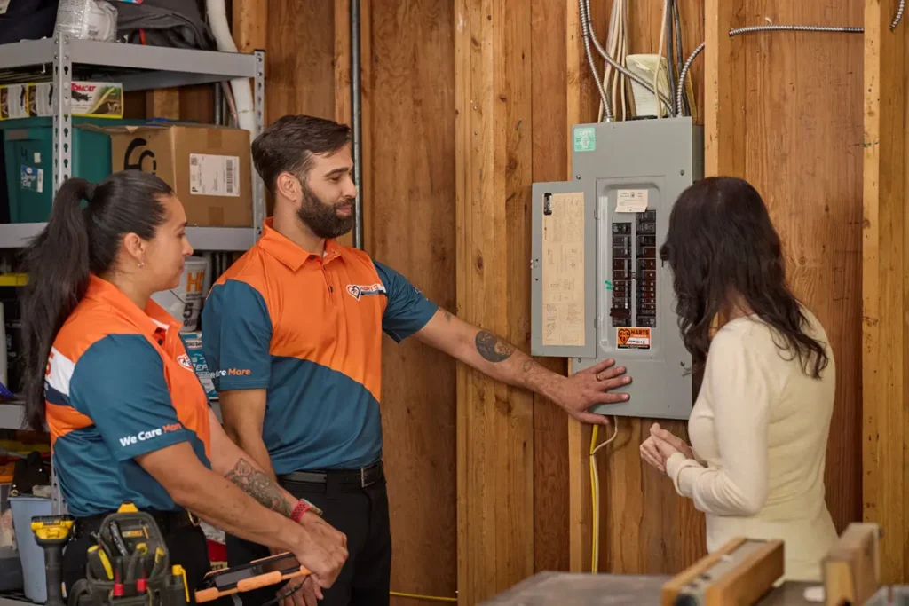 Harts electricians discussing an electrical panel upgrade with a homeowner in a garage.