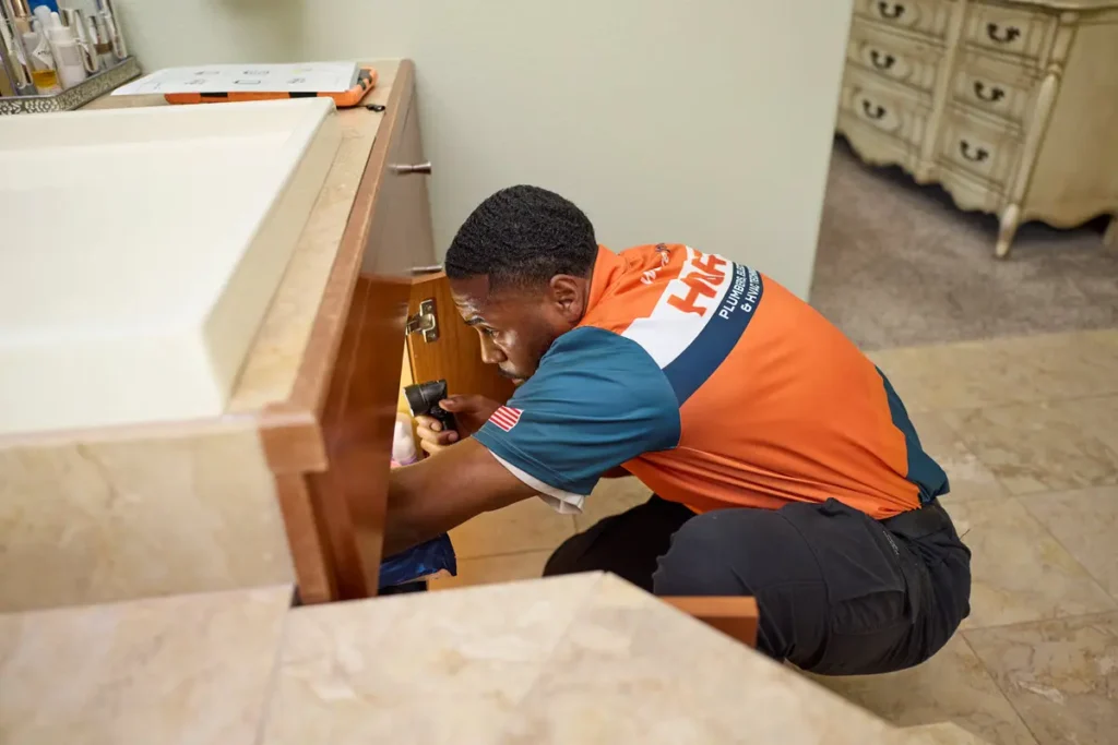 Harts technician inspecting plumbing under a bathroom sink