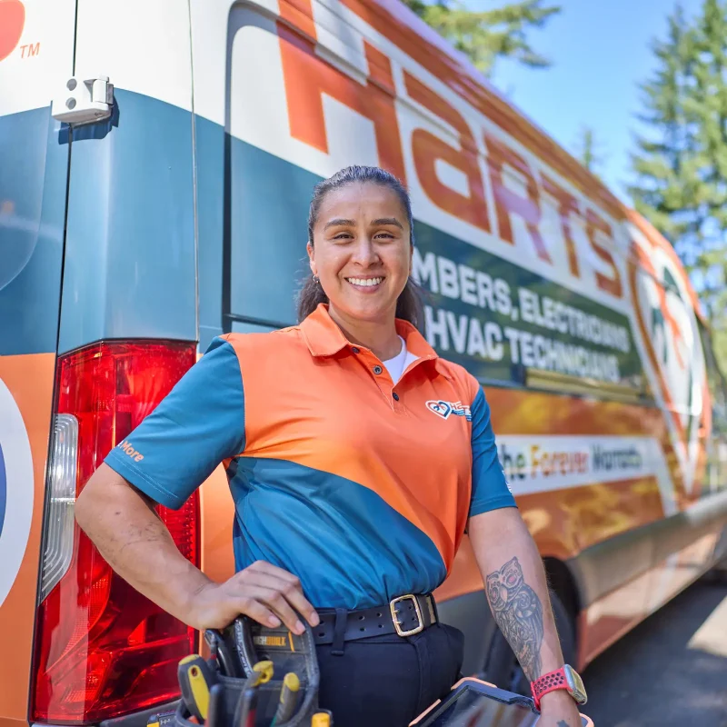 Harts technician in branded uniform standing beside a Harts service van in Renton