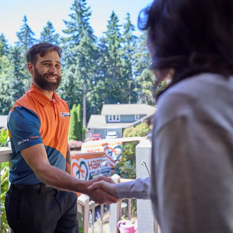 Harts technician greeting a homeowner with a branded service van in the driveway
